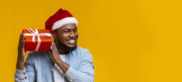 Alegre hombre negro en santa sombrero sacudiendo la caja de regalo de Navidad — Foto de Stock