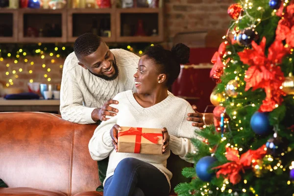 Чорний хлопець дарує свою дівчину подарункову коробку, вітаючи з Різдвом — стокове фото