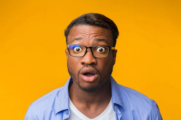 Verrast Afro-Amerikaanse man op zoek naar camera poseren, gele achtergrond — Stockfoto