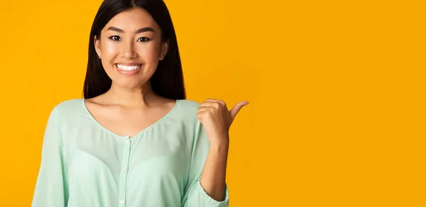 Sorridente ragazza asiatica indicando da parte a copia spazio — Foto Stock