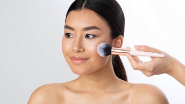 Makyaj sanatçısı fırçayla yanaklarına allık sürüyor