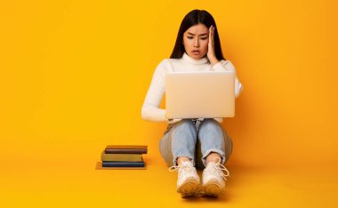 Hayal kırıklığına uğramış öğrenci kız dizüstü bilgisayara bakıyor.