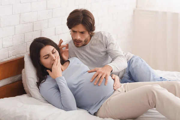 Pregnant woman suffering from morning nausea, worried husband soothing her. — ストック写真