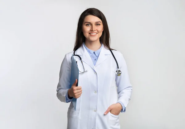 Terapeuta Lady sonriendo en la cámara sosteniendo la carpeta sobre fondo gris —  Fotos de Stock