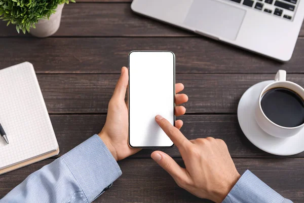 Çalışma alanında boş ekranlı akıllı telefon kullanan tanınmayan bir adam