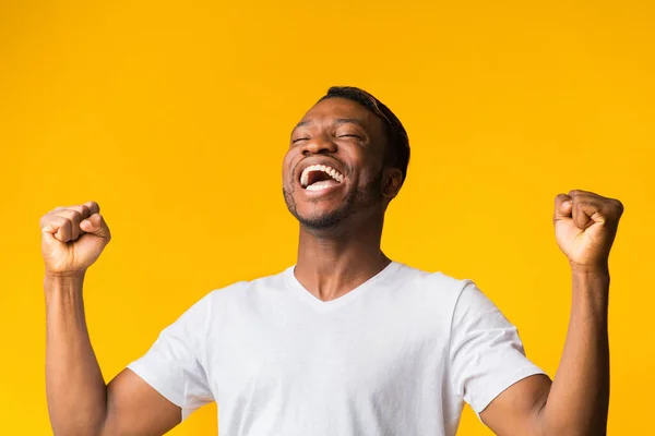 Gelukkig zwart man schreeuwen en schudden vuisten over gele achtergrond — Stockfoto