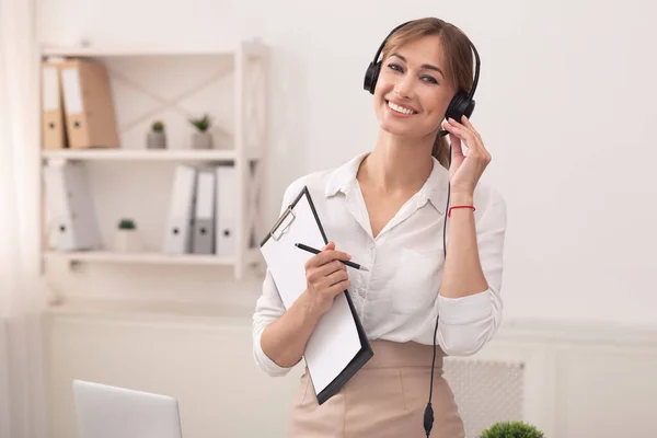 고객 지원 사무실에 서 있는 헤드폰을 쓴 채웃고 있는 소녀 — 스톡 사진