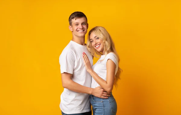 Porträtt av unga romantiska par kramas på gul bakgrund — Stockfoto