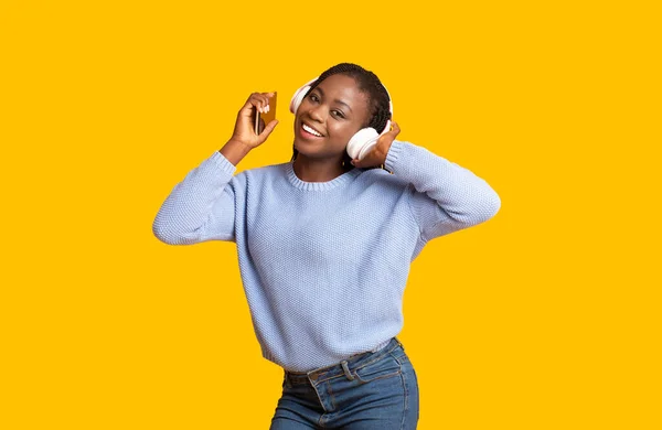 Zwart meisje luisteren naar muziek, met behulp van telefoon en draadloze headset — Stockfoto
