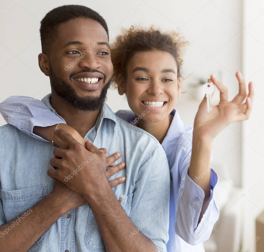 Happy Black Couple Hugging Showing Key Standing In New Home