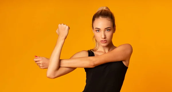 Γυμναστική κυρία τεντωμένο χέρι κάνει άσκηση όρθια, κίτρινο φόντο, Πανόραμα — Φωτογραφία Αρχείου
