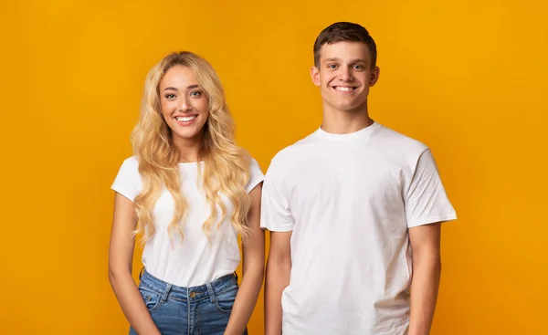 Portrait de sourire millénariste gars et fille sur fond jaune — Photo