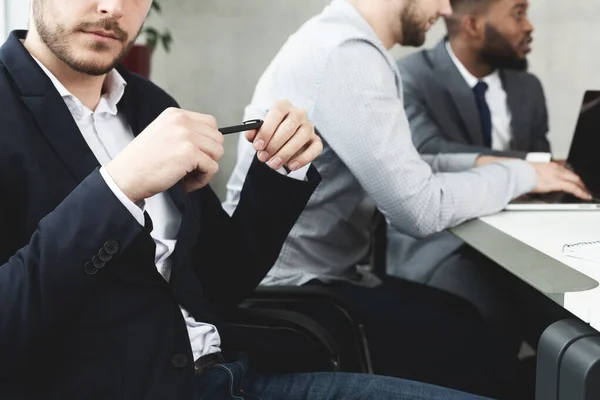 Jeune homme d'affaires avec stylo dans les mains lors d'une réunion de conférence — Photo