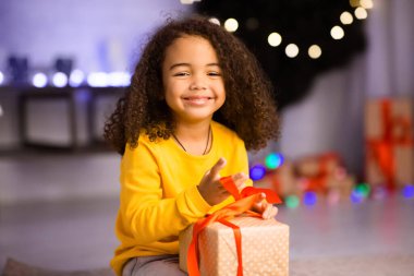 Sevimli Afrikalı Amerikalı çocuk Noel hediyesini evde yiyor.