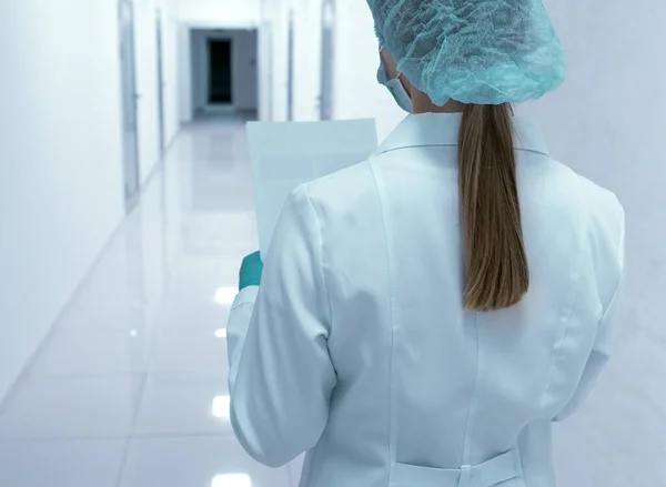 Doctora mirando documentos dentro del pasillo médico vacío — Foto de Stock