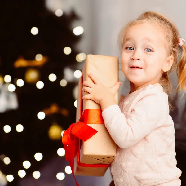 Adorable niño sosteniendo presente caja cerca del árbol de Navidad —  Fotos de Stock