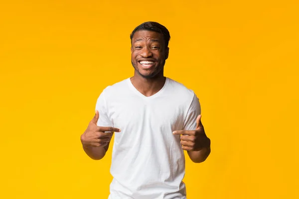 Negro hombre apuntando dedos a sí mismo sonriendo sobre amarillo fondo — Foto de Stock