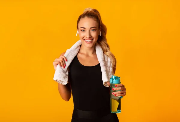 Χαρούμενη κυρία στα ακουστικά που κρατά μπουκάλι και πετσέτα νερού, Studio — Φωτογραφία Αρχείου