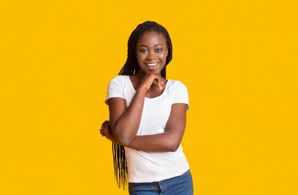 Interessado senhora negra sorrindo sobre fundo amarelo — Fotografia de Stock