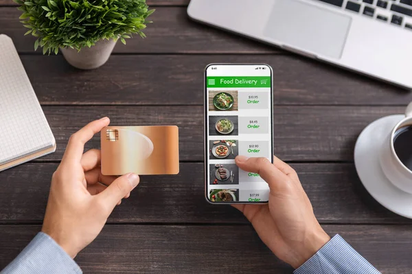 Άνδρας που χρησιμοποιεί πιστωτική κάρτα και smartphone με εφαρμογή παράδοσης τροφίμων — Φωτογραφία Αρχείου