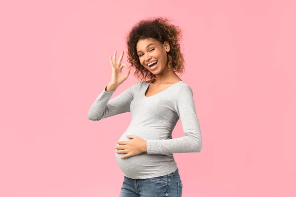 Femme enceinte afro-américaine montrant un geste correct, fond rose — Photo