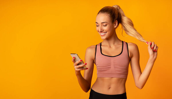 Sporty Woman Using Cellphone During Training Standing Over Yellow Background