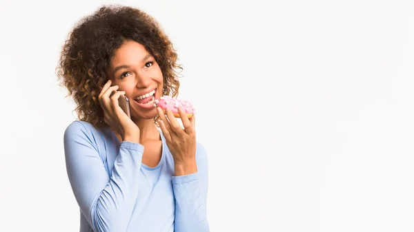 Mujer embarazada comiendo donut y hablando por teléfono — Foto de Stock