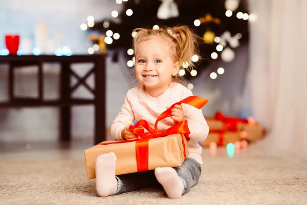 Curiosa niña abriendo regalo de Navidad en casa —  Fotos de Stock