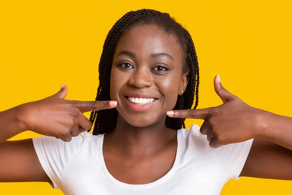 Primer plano de chica sonriente apuntando a sus dientes blancos — Foto de Stock