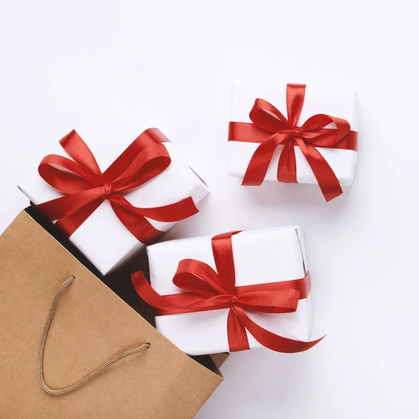 Wiele prezentów świątecznych z czerwonymi wstążkami i torbą na zakupy — Zdjęcie stockowe