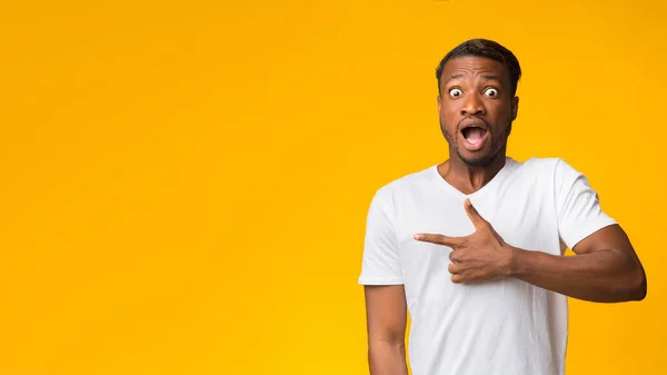 Geschokte Afro Guy wijzende vinger naast staande, gele achtergrond, Panorama — Stockfoto