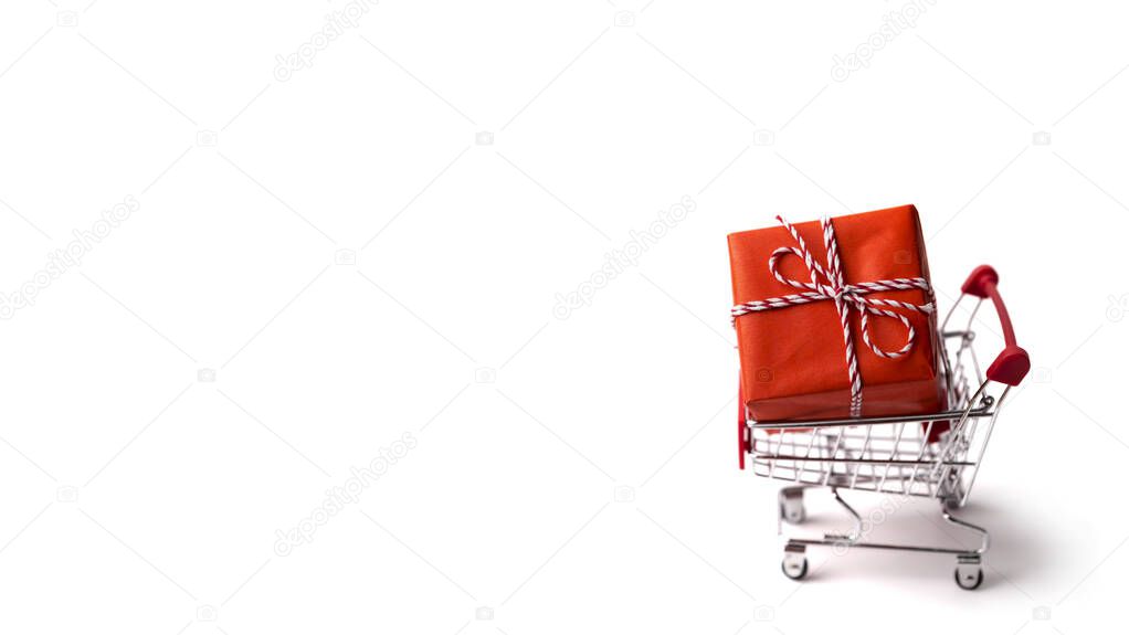 Shopping cart with big gift box on white background