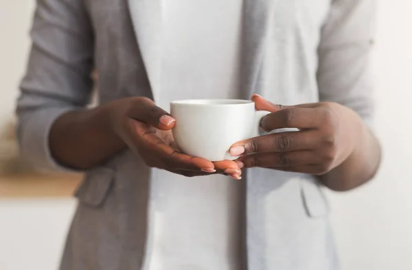 Tasse Kaffee in den Händen einer bis zur Unkenntlichkeit schwarzen Geschäftsfrau — Stockfoto