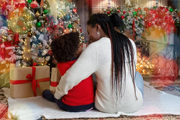 Amante mãe abraçando sua filha enquanto se sentam juntos perto da árvore de Natal — Fotografia de Stock