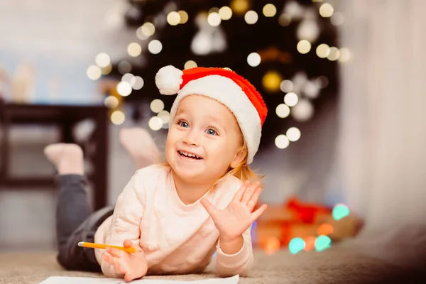 Niña dibujando en el suelo cerca del árbol de Navidad —  Fotos de Stock