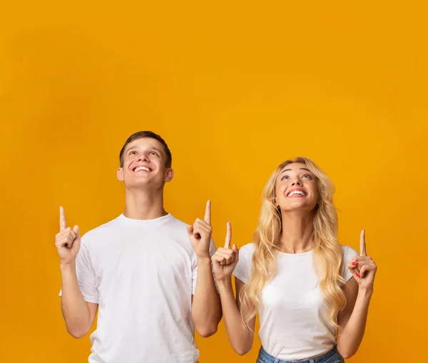 Smiling youngsters pointing and looking upwards at copy space — Stock Photo, Image