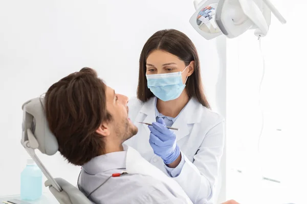 Vrouwelijke tandarts maken check-up voor mannelijke patiënt — Stockfoto