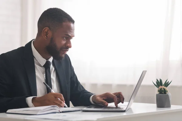 Secretario de negocios concentrado tomando notas, utilizando el ordenador portátil —  Fotos de Stock