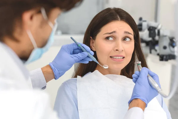 Mulher assustada no consultório odontológico, olhando em pânico para o dentista — Fotografia de Stock