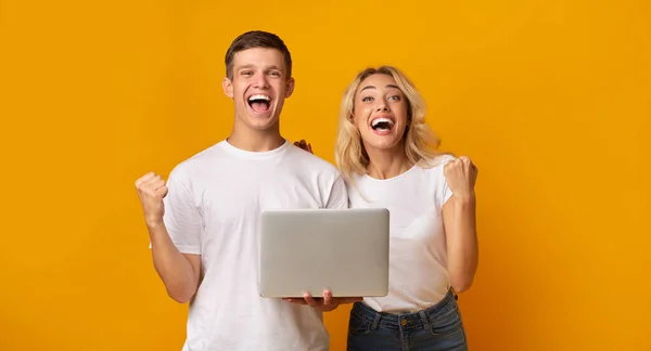 Alegre joven y chica celebrando ganar con el ordenador portátil —  Fotos de Stock