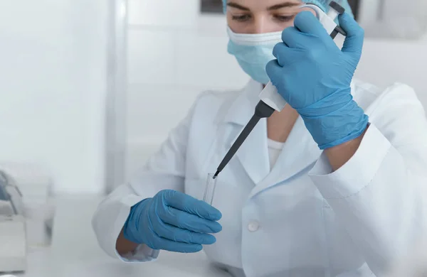 Junge Wissenschaftlerin mit großer Spritze, die ins Reagenzglas tropft — Stockfoto