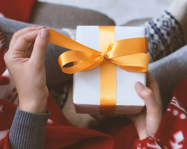 Female hands opening New Year gift with yellow ribbon — Stock Photo, Image