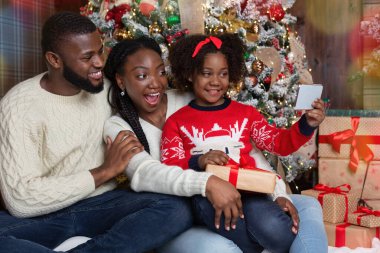 Küçük afro kız Noel ağacının yanında ailesiyle selfie çekiyor.