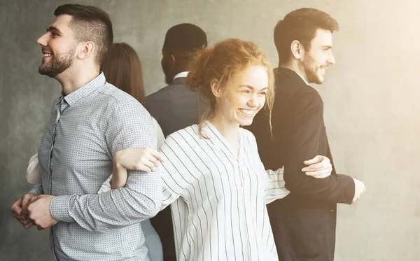 Jeunes gens d'affaires debout en cercle dos à dos et souriant — Photo