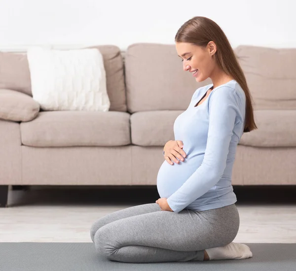 Oldalnézet terhes lány tartja a hasát — Stock Fotó