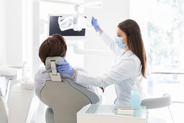 Kadın dişçi sandalyesinde oturan hastasını selamlıyor. — Stok fotoğraf