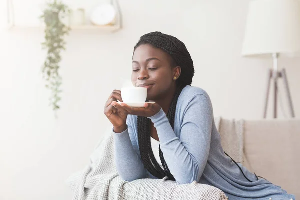 Afro γυναίκα χαλαρώνοντας στο σπίτι με φλιτζάνι καφέ — Φωτογραφία Αρχείου
