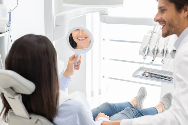 Sattisfied woman client of dental clinic smiling at mirror — Stock Photo, Image