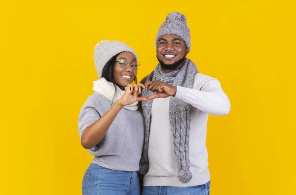 Glückliches junges Winterpaar zeigt Herzzeichen mit Fingern — Stockfoto