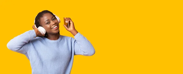 Happy african girl enjoying music over yellow background — Stock Photo, Image